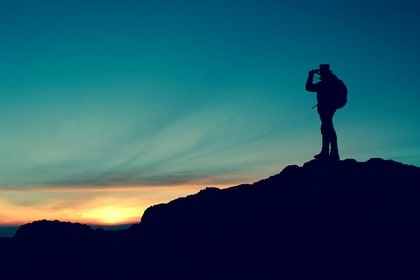 man looking with binoculars at dusk sky