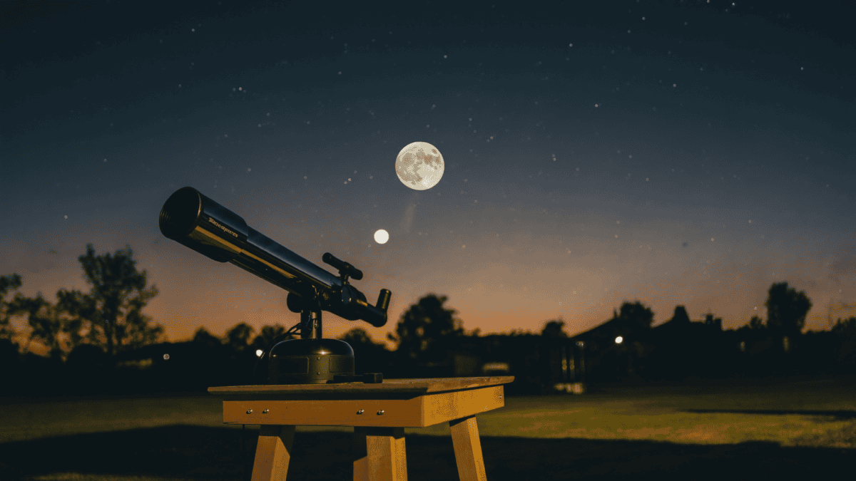 A beginner tabletop telescope in a suburban backyard under a light-polluted, Moon-bright sky