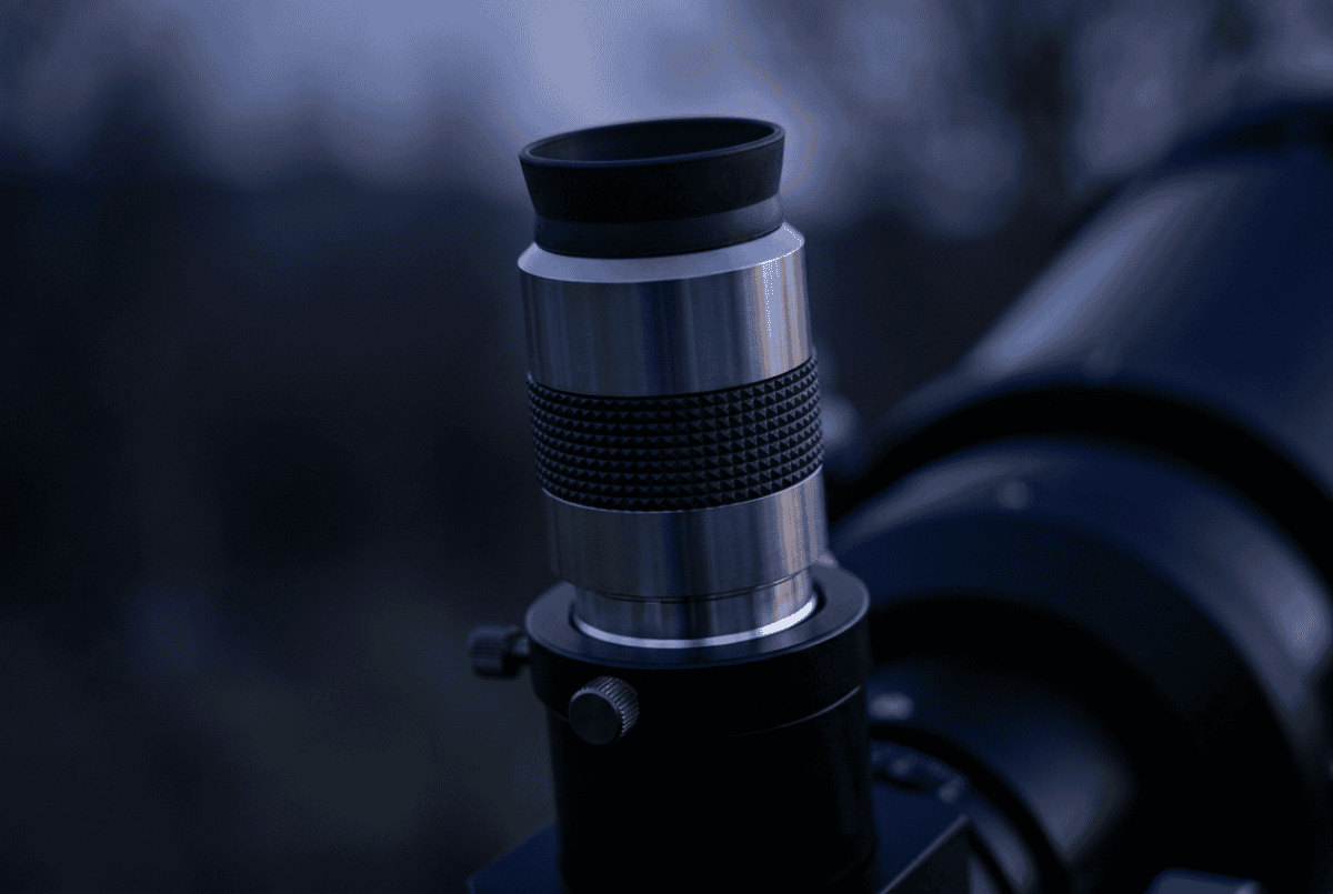 A telescope eyepiece seated in a focuser at dusk